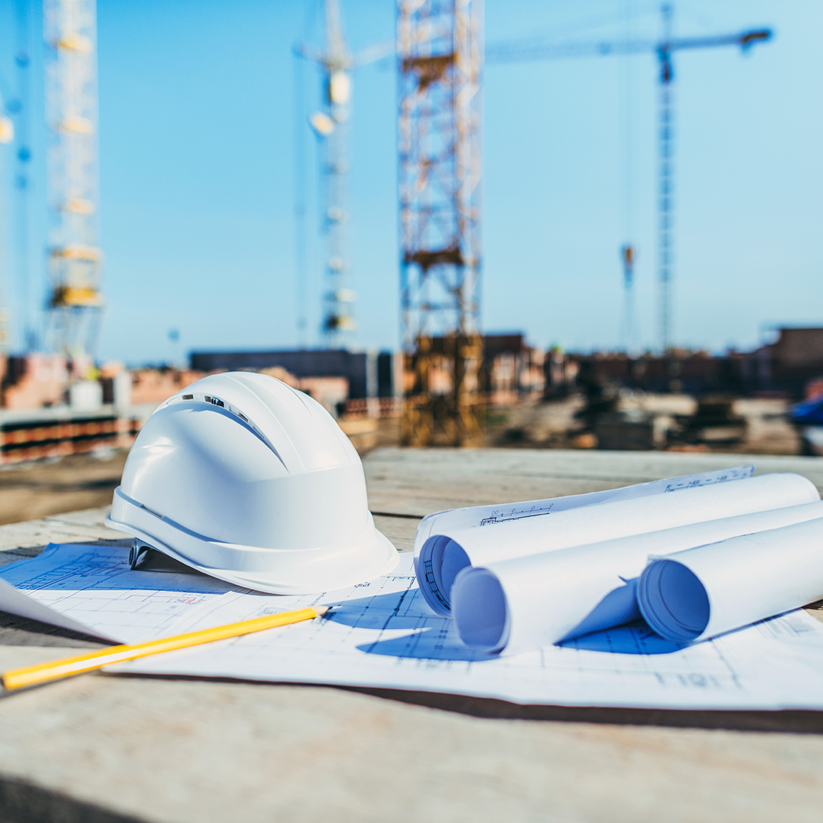 close-up shot of rolls of papers with building plans and hardhat